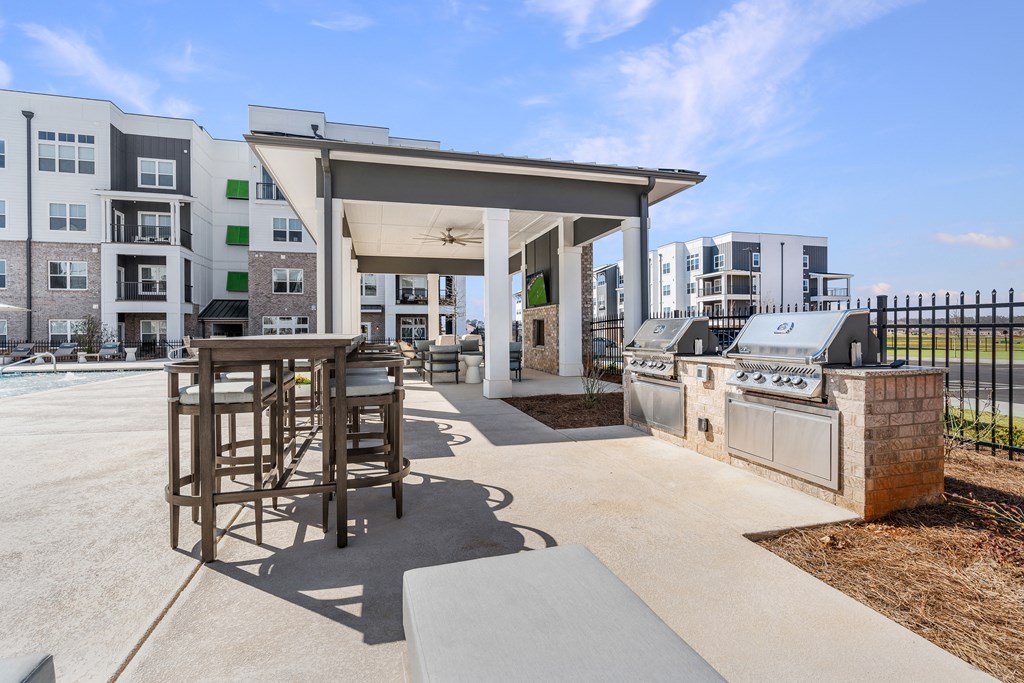 a patio with a barbecue grill and a bar with stools