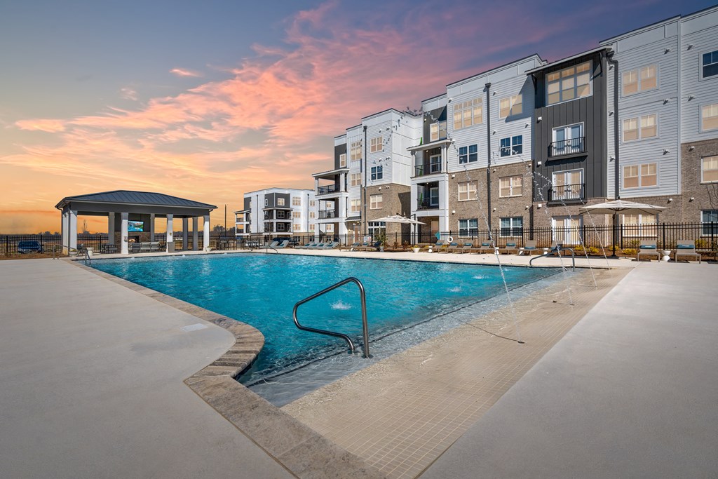 a swimming pool in front of an apartment building at sunset