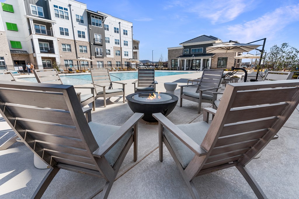 an outdoor patio with chairs and a fire pit and a pool
