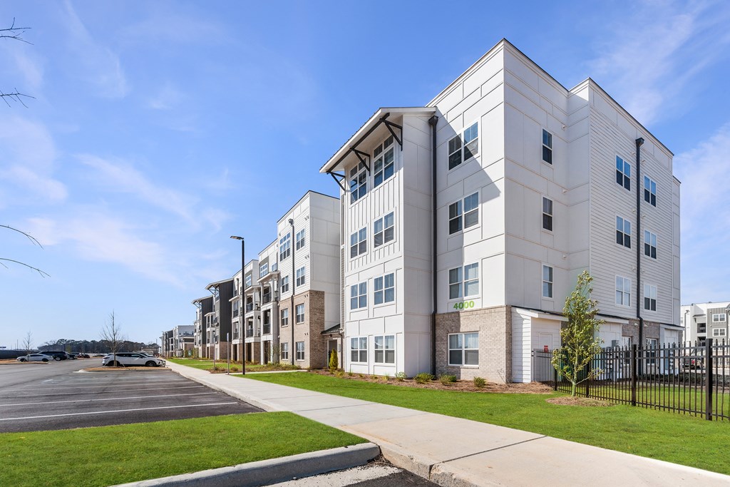 an apartment building with a sidewalk and a parking lot