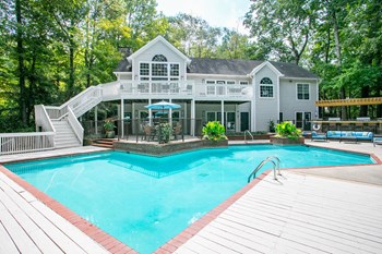 View of clubhouse with large pool, chairs and umbrellas.