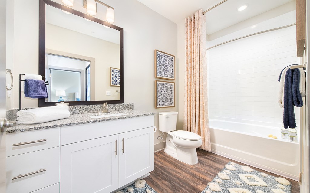Bathroom with wood-designed flooring, large vanity counter, and shower/tub at The Highland