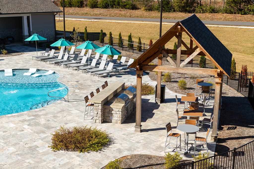 The Alexandira poolside grilling pavilion with gas grills, bar-style seating, and tables next to resort style swimming pool in Madison, AL