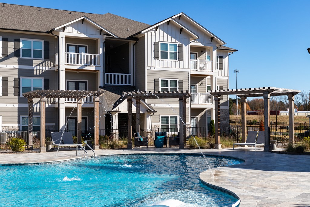 Poolside lounging pavilions with pergola shading and seating next to resort-style swimming pool at The Alexandria