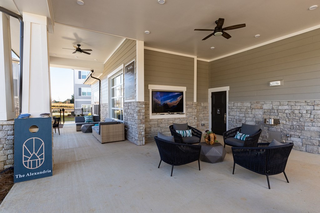 Outdoor resident lounge with seating, TV, and concrete flooring at The Alexandria in Madison, AL