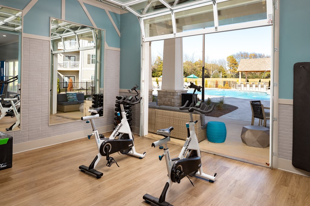 Premium fitness center with exercise machines, wood-designed flooring, wide windows, and high ceiling at The Alexandria