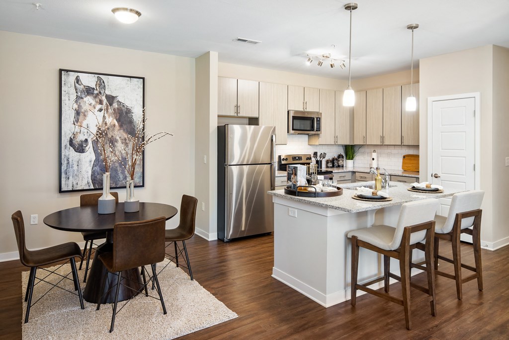 Furnished dining area of an apartment with dining chairs and table with wood-designed flooring at The Alexandria in Madison, AL