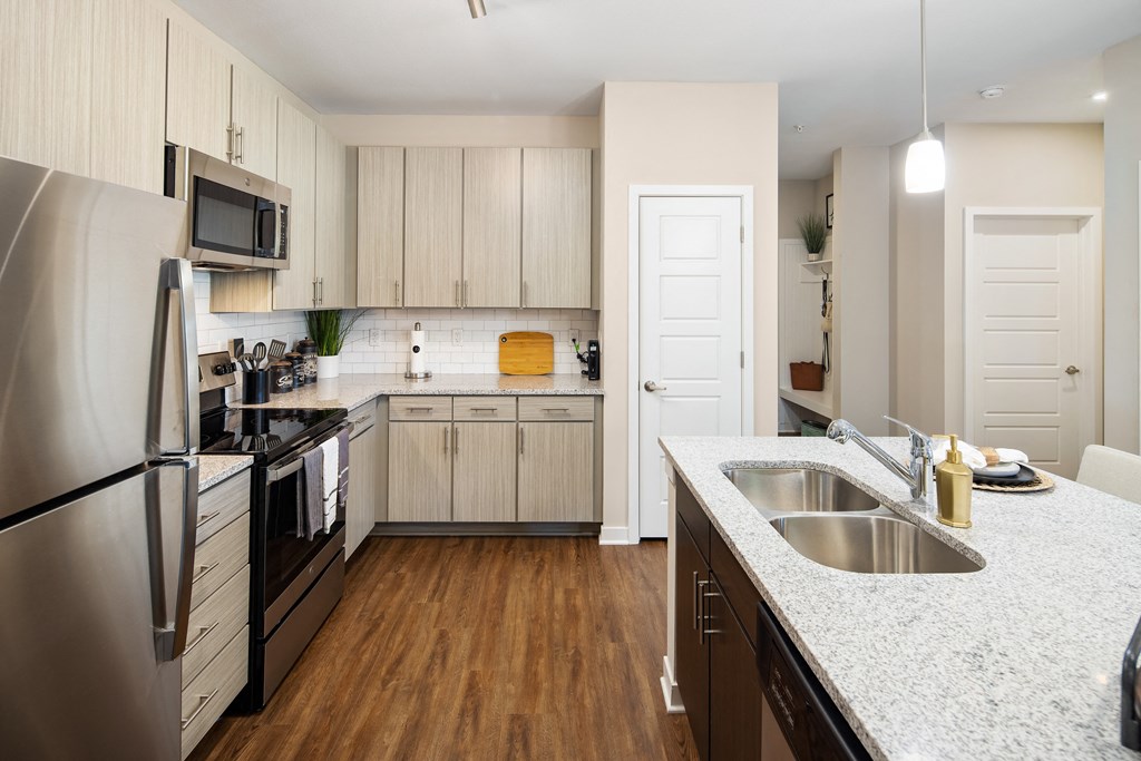 Kitchen with granite countertops, stainless steel appliances, subway tile backsplash and wood-designed flooring at The Alexandria in Madison, AL