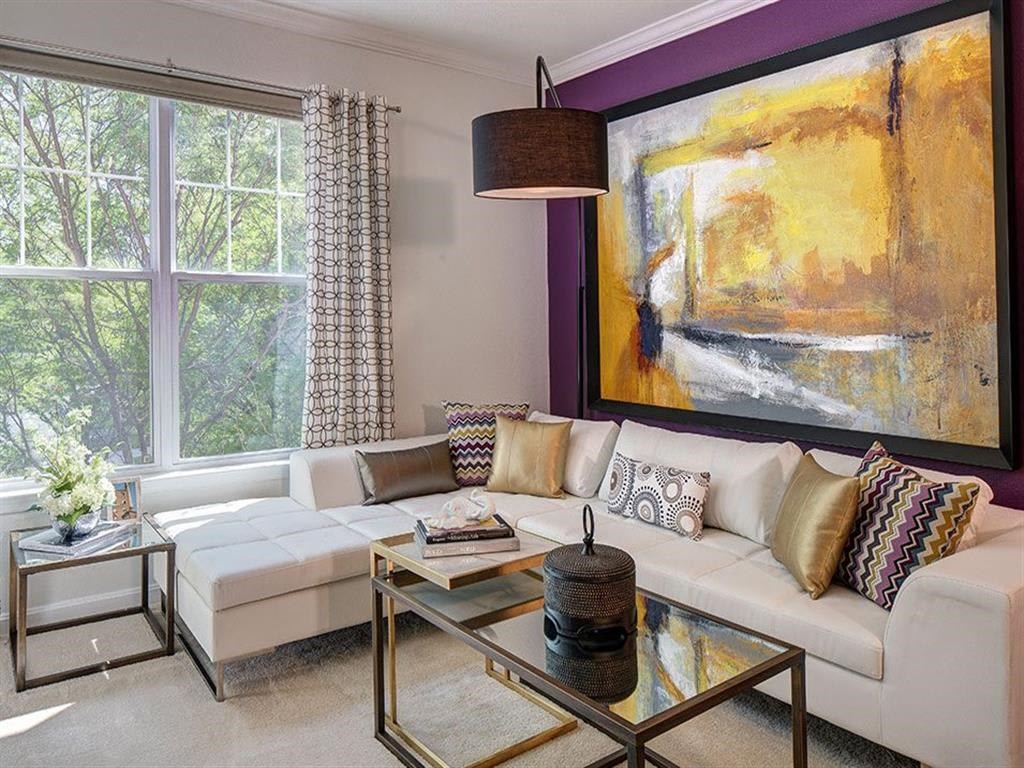 a living room with a white couch and a large painting on the wall