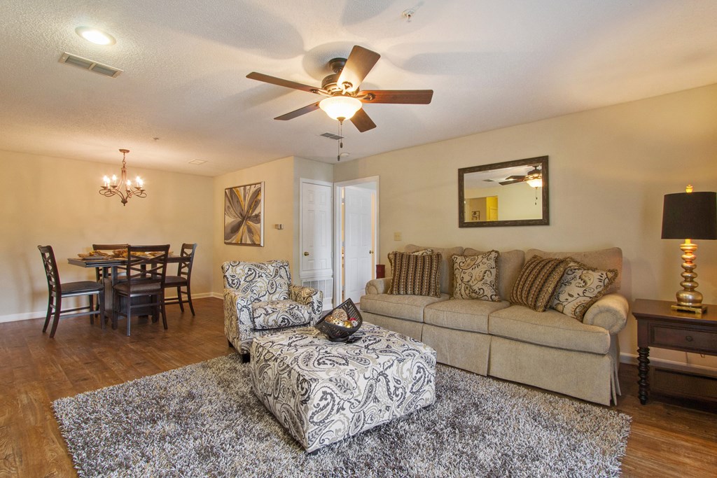 Spacious living and dining area with wood-designed flooring, sofas, dining tables at The Gables apartments in Ridgeland, MS