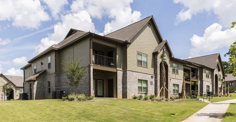 A large, modern house with a grey exterior and a well-maintained lawn.