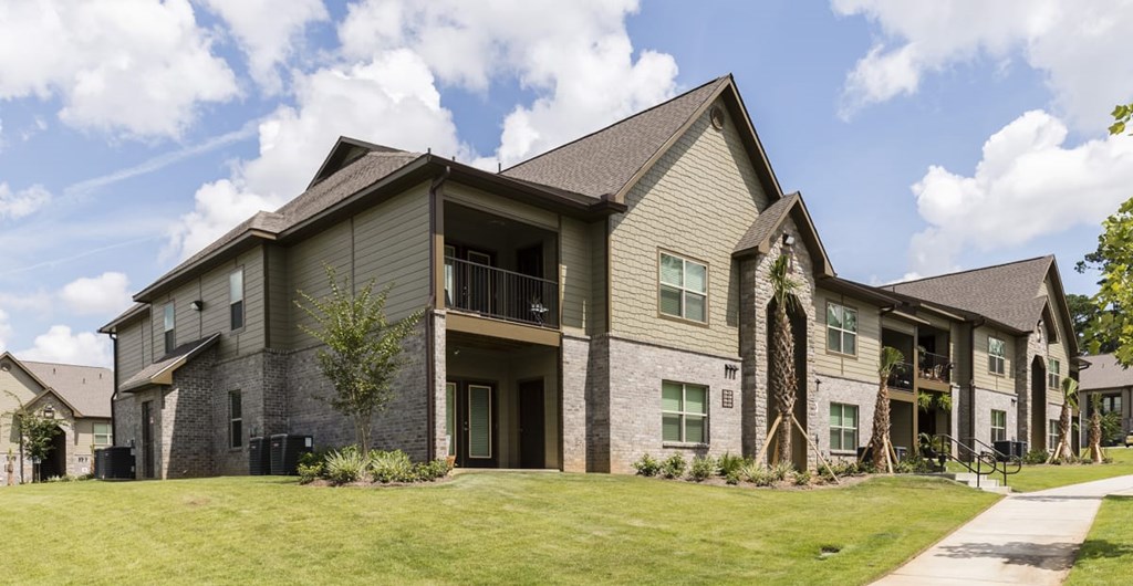 A large, modern house with a grey exterior and a well-maintained lawn.