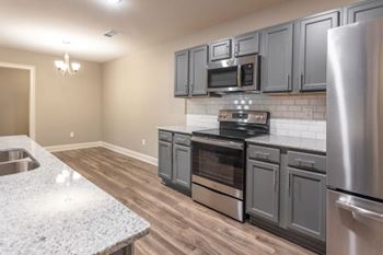 A kitchen with stainless steel appliances and wooden floors.