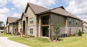 A large house with a grey roof and a green lawn in front.
