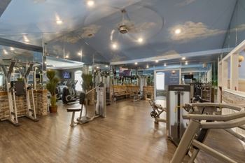 A gym with a variety of equipment including treadmills, weights, and exercise machines.
