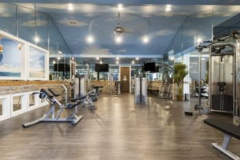 A gym with a variety of equipment including treadmills, weights, and exercise machines.
