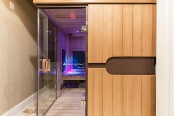 A room with a glass door leading to a purple room with a bed and a sign that says sunlight.
