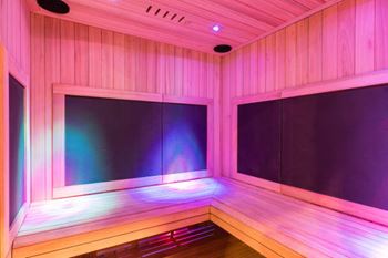 A room with wooden walls and a bench with a pink light.