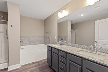 A bathroom with a white tub and dark grey cabinets.