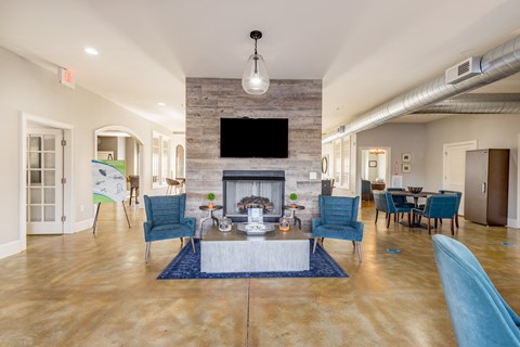 a living room with a fireplace and blue chairs and a table