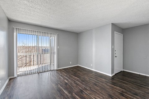 an empty living room with a large window and wood flooring