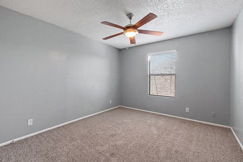 an empty room with a ceiling fan and a window