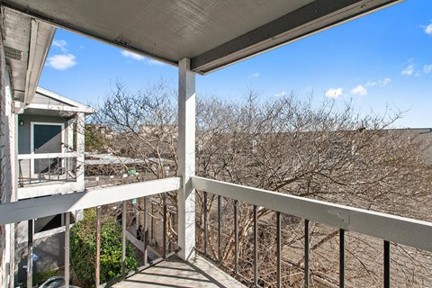 the balcony has a view of the trees and the house