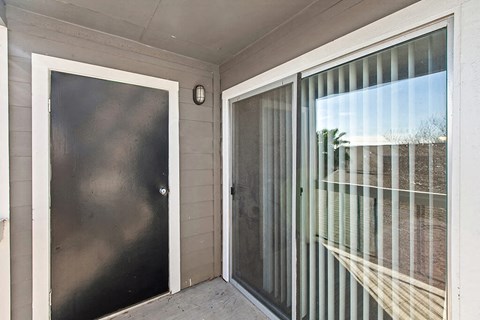 the front door of a home with a glass screen door and a patio