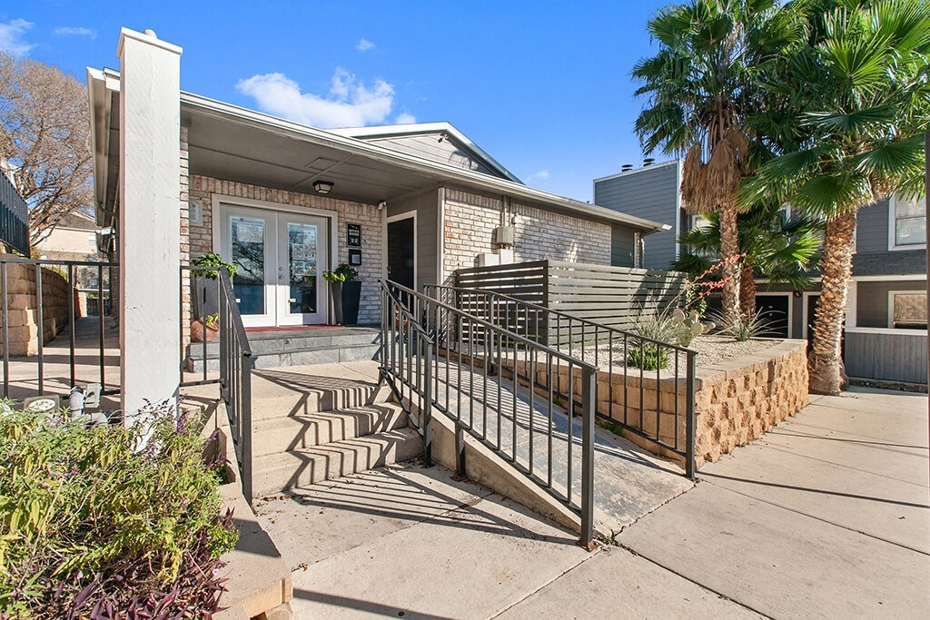 the front of a house with a staircase and a wrought iron gate