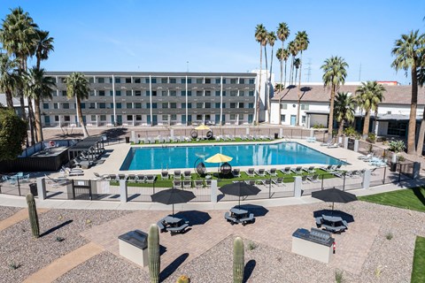 A pool surrounded by chairs and umbrellas with a building in the background at Presidio Palms Apartments, Tucson, AZ, 85701