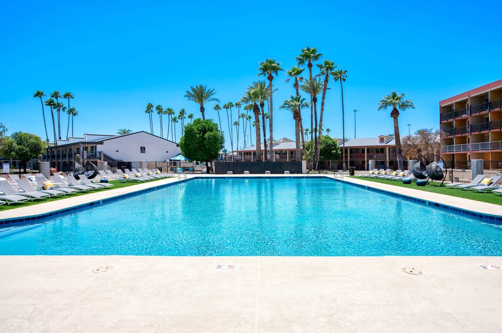 a large pool with palm trees in front of a hotel at Presidio Palms Apartments, Tucson