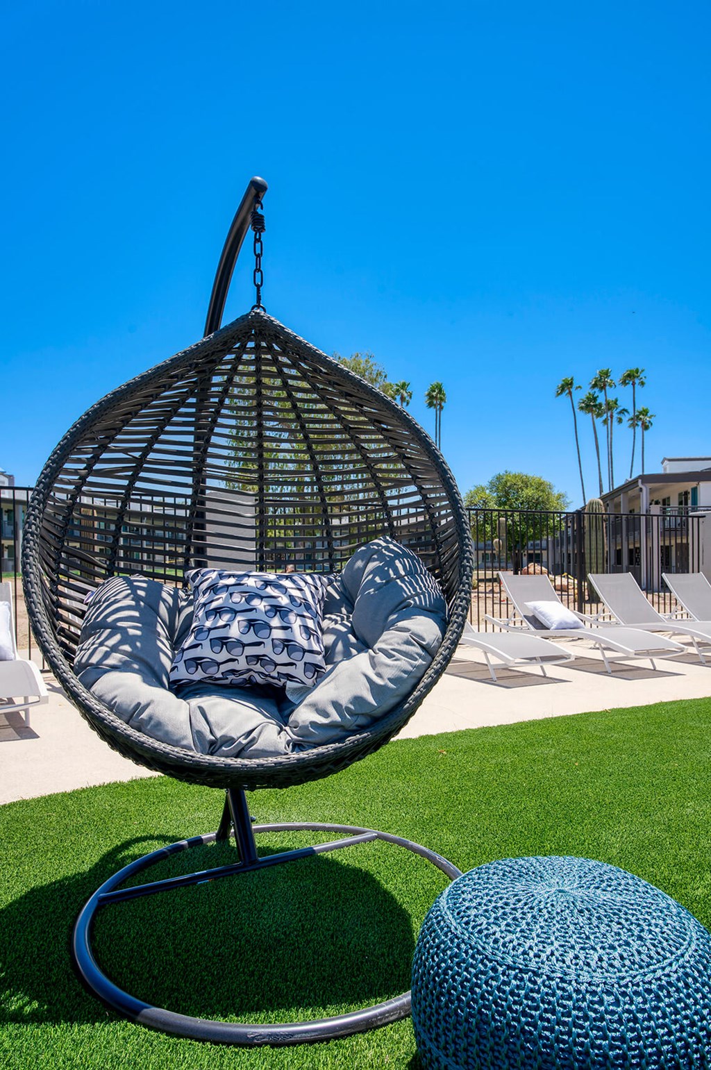 a swing chair with pillows on the grass at a pool at Presidio Palms Apartments, Tucson, Arizona