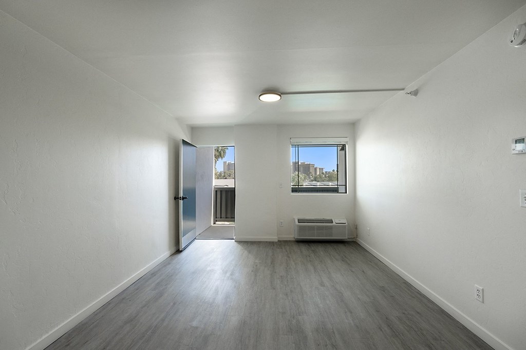 A spacious room with a door leading to a balconyat Presidio Palms Apartments, Tucson