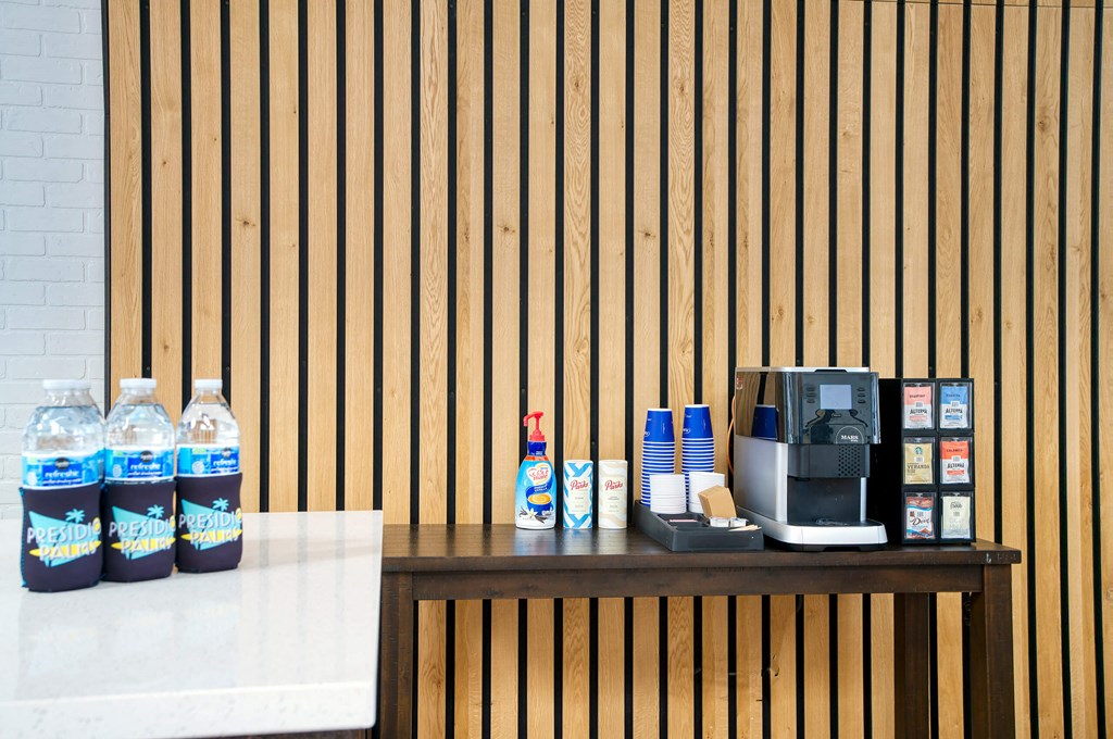 a counter with a coffee machine and water bottles at Presidio Palms Apartments, Tucson, Arizona