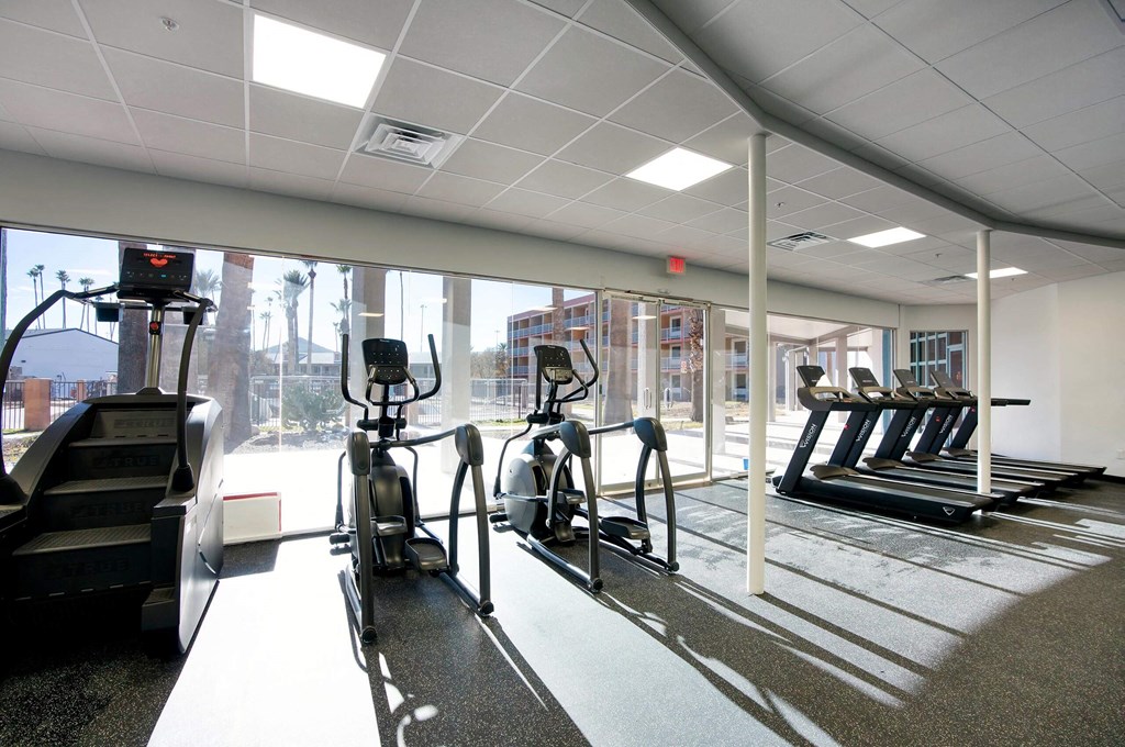 a gym with cardio equipment and a large window at Presidio Palms Apartments, Tucson, 85701