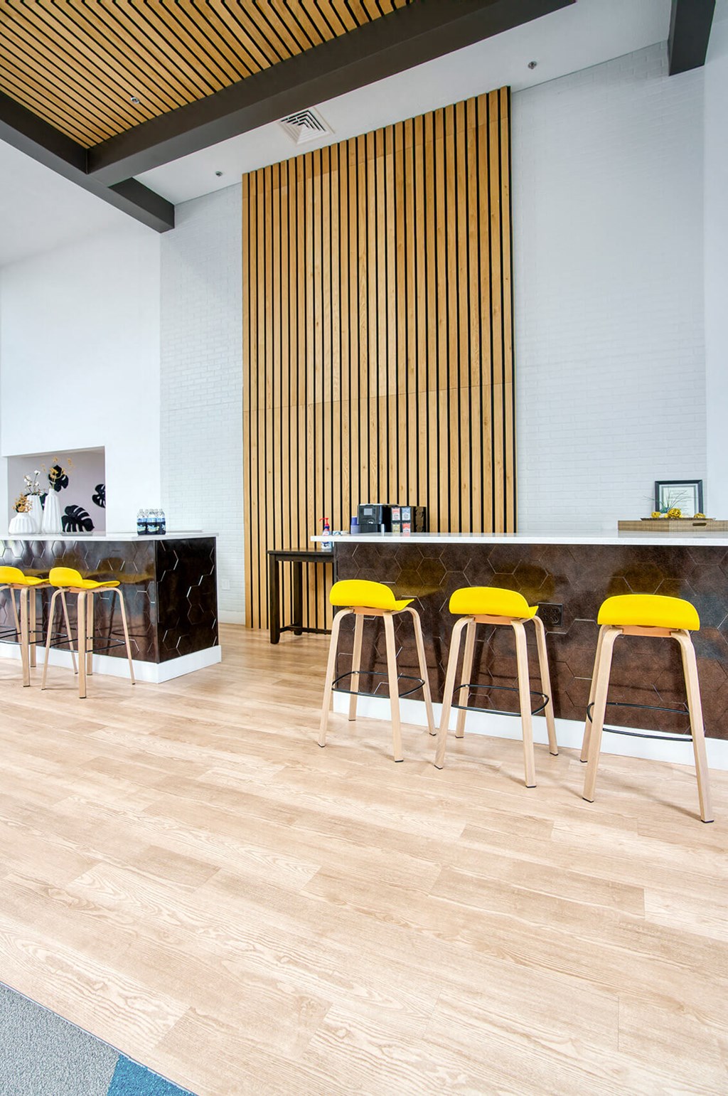 a bar with yellow bar stools in front of a counter with chairs at Presidio Palms Apartments, Tucson, Arizona