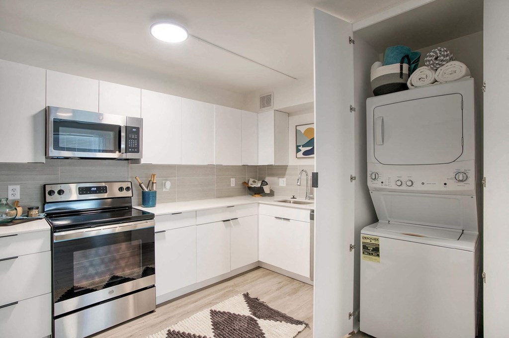 a white kitchen with stainless steel appliances and white cabinets at Presidio Palms Apartments, Arizona