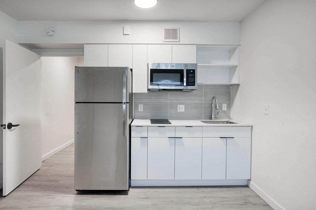 a kitchen with refrigerator and white cabinets at Presidio Palms Apartments, Tucson, AZ