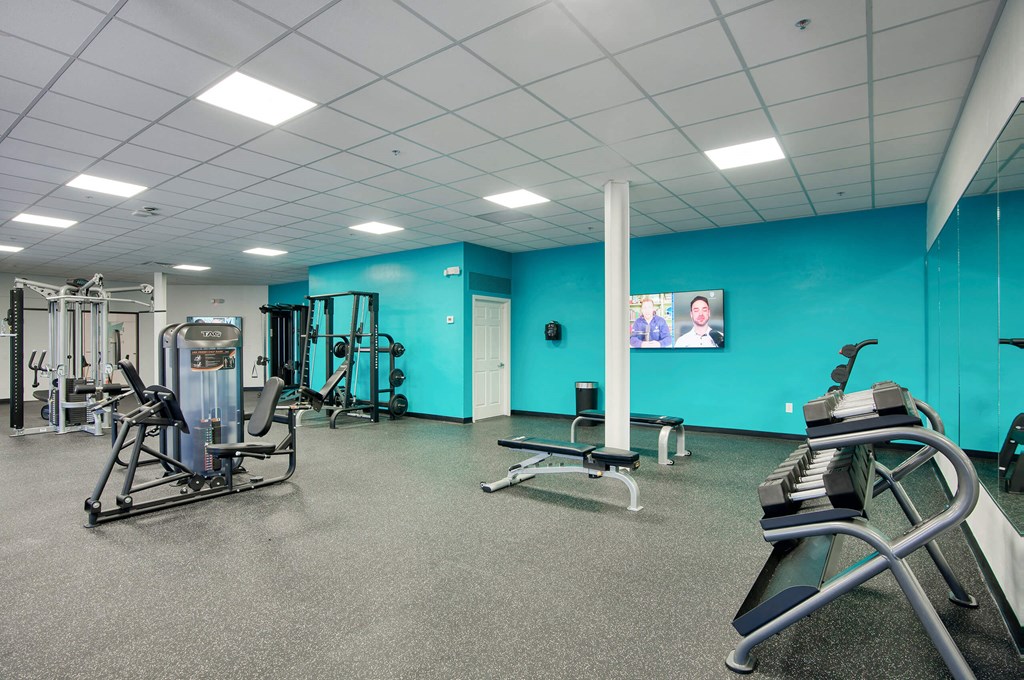 a gym with weights and cardio equipment and a tv at Presidio Palms Apartments, Tucson