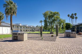 A sunny day at a courtyard with palm trees and a building in the background.