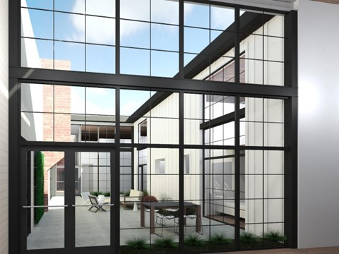a courtyard with large glass windows and a table and chairs at American Spinning Mill, Greenville, South Carolina