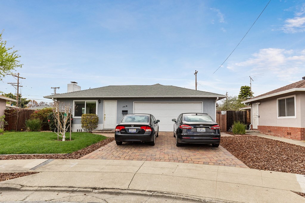 Two cars are parked in front of a house.
