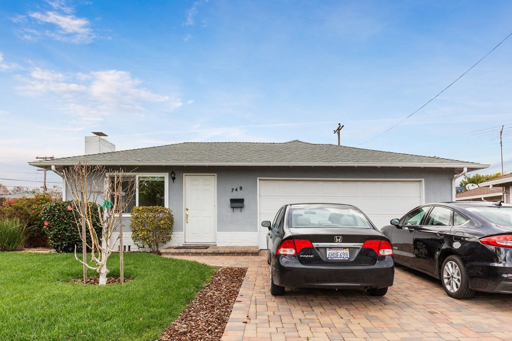 Two cars are parked in front of a house.