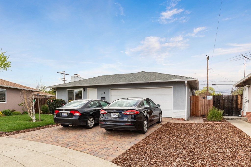 Two cars are parked in front of a house.