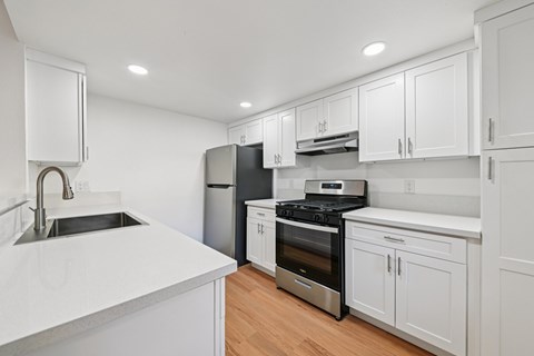 A modern kitchen with white cabinets and stainless steel appliances.