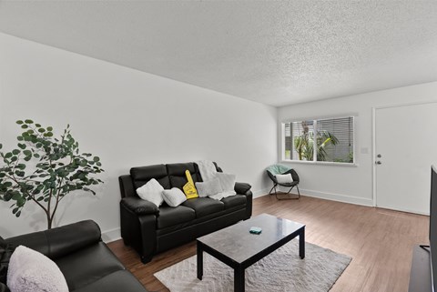 A black leather couch with a yellow pillow sits in a living room with a black coffee table.