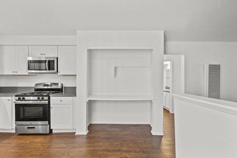 A white kitchen with a stove, oven, microwave, and cabinets.