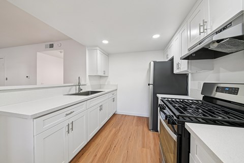 A modern kitchen with white cabinets and a black stove top.