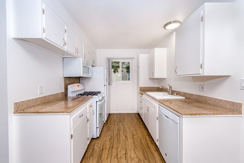 A kitchen with white cabinets and a counter top.