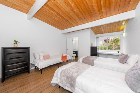 A bedroom with a white bed and a wooden ceiling.